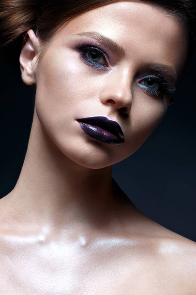 Young girl with creative makeup and hairdo. A beautiful model with bright eyes and purple lips. Shining skin. - Photo, image