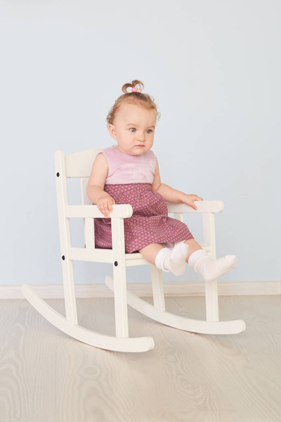 beautiful little girl in a dress sits on a white chair - Foto, Bild