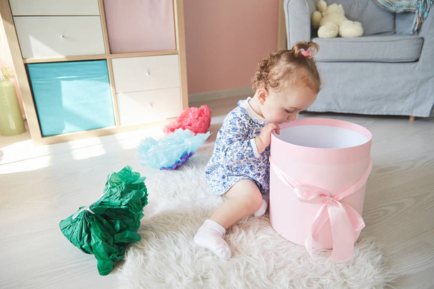 baby girl opens the gift. pink box with bow - Foto, Bild