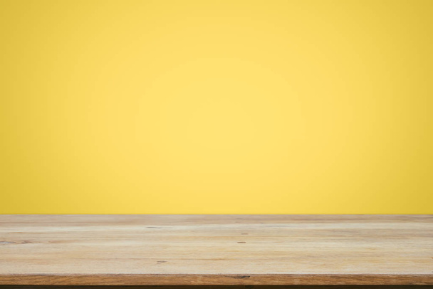 Empty wooden deck table over yellow wallpaper background. - Photo, Image