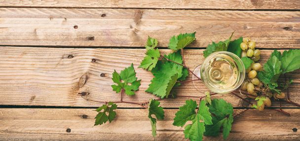 Bicchiere di vino bianco e uva fresca su sfondo di legno, spazio copia
 - Foto, immagini