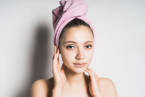 beautiful girl with clean skin, with a pink towel on her head looking at the camera - Foto, afbeelding