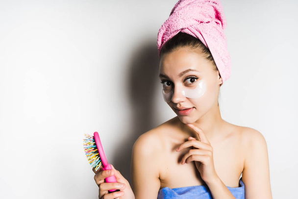 beautiful cute girl with a pink towel on her head, holds a comb in her hand, looks into the camera - Foto, Bild