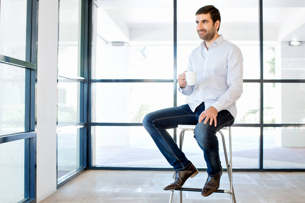Young business man sitting on a stool in office - Photo, image