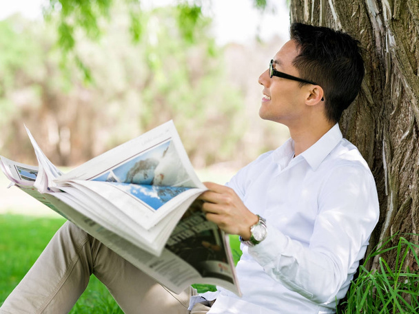 Business man reading a newspaper in park - Zdjęcie, obraz