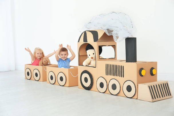Little children playing with cardboard train in light room - Foto, Imagen