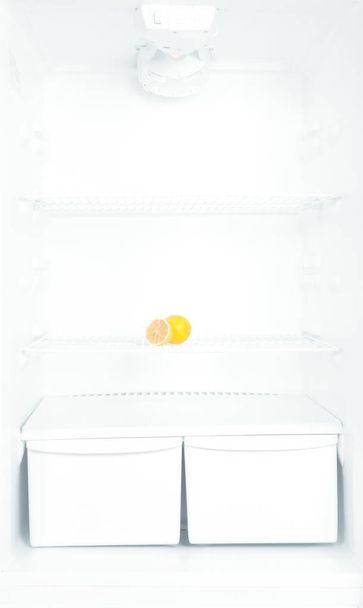Diet concept. Lemon on shelf of open empty refrigerator. - Фото, зображення