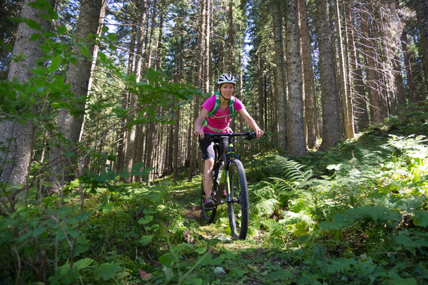 Active sporty woman riding mountain bike on forest trail . - Zdjęcie, obraz