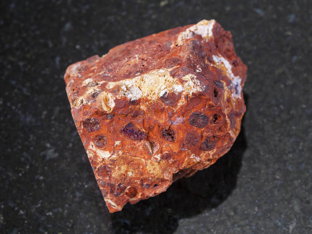 грубый красный бокситовый камень на темном фоне
 - Фото, изображение