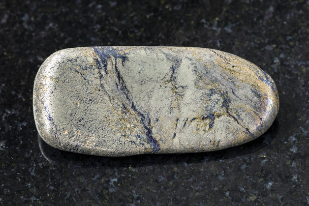 piedra de arsenopirita pulida sobre fondo oscuro
 - Foto, imagen