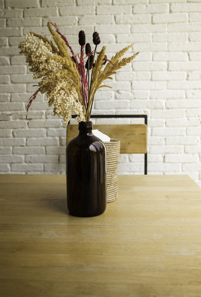 Dried flowers in a vase on wooden table - Foto, afbeelding