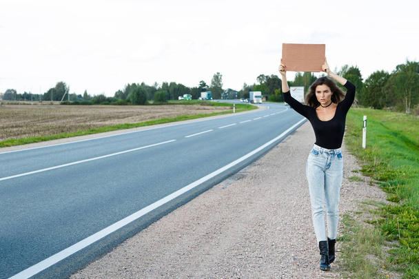 Young woman hitchhiker on road  - Фото, зображення