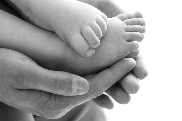 赤ちゃんの足を保持している父親の手 - 写真・画像