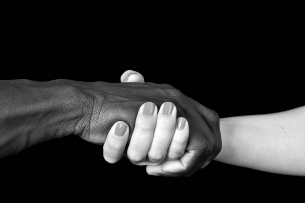 Egy fekete férfi és fekete háttér fehér nő kezében - Fotó, kép