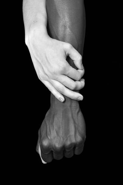 Τα χέρια ένα μαύρο άντρα και λευκή γυναίκα, σε μαύρο φόντο - Φωτογραφία, εικόνα