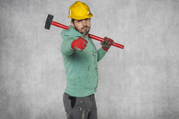 worker with a big hammer on his shoulder, thumb up - Фото, изображение