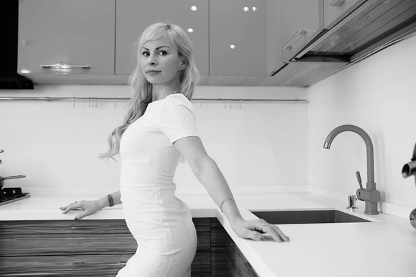 Foto in bianco e nero di ragazza bionda in posa sulla macchina fotografica in cucina
 - Foto, immagini