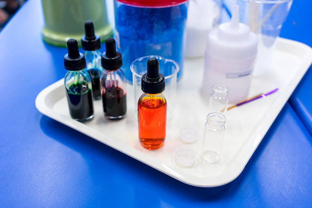 Un conjunto de colores y productos químicos con equipo de laboratorio en plástico blanco
 - Foto, Imagen