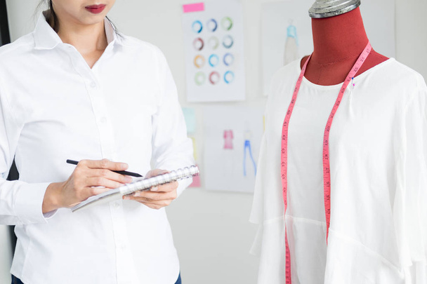 Asian tailor adjusts garment design on mannequin in workshop mak - Fotografie, Obrázek