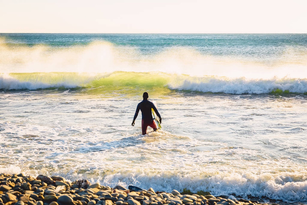 Surffaaja auringonlaskun aikaan. Talvi surffaus uimapuvussa
 - Valokuva, kuva