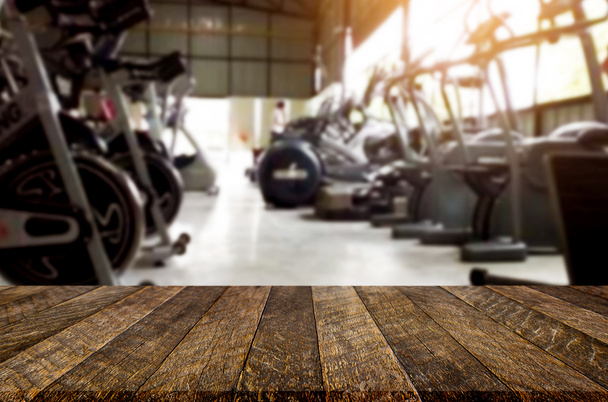 Wooden table on blurred background of fitness gym interior of mo - Photo, Image