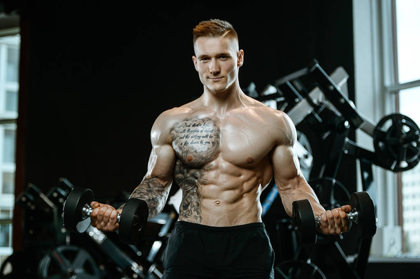 Handsome model young man training arms in gym - Photo, Image