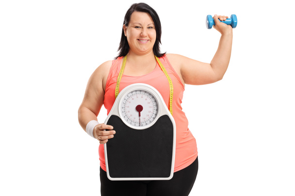 overweight woman with a weight scale and a dumbbell - Foto, afbeelding