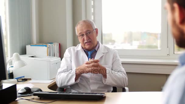 senior doctor talking to male patient at hospital - Materiał filmowy, wideo