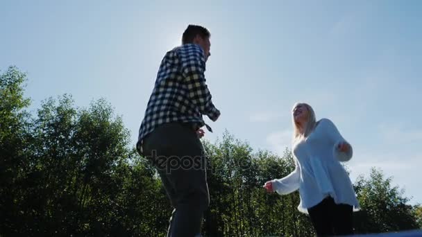 Jump high toward the sun. Young multiethnic couple having fun together. Slow motion video - Video