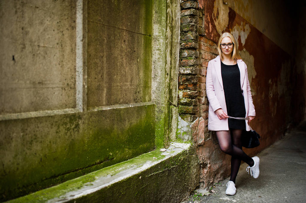 Blonde girl at glasses and pink coat, black tunic and handbag po - Fotografie, Obrázek