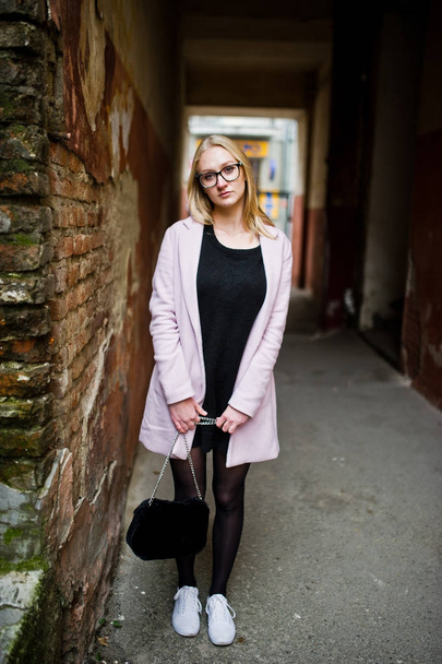 Blonde girl at glasses and pink coat, black tunic and handbag po - Foto, afbeelding