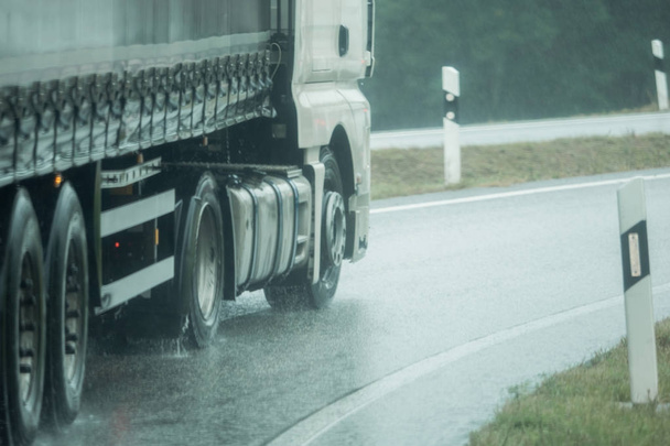 Un camión está conduciendo en la carretera bajo la lluvia
 - Foto, imagen