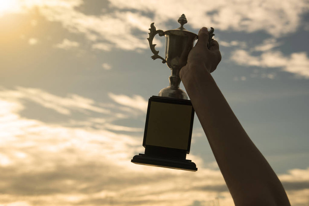 silhouet hand hebt winnaar trofee cup in een kampioenschap  - Foto, afbeelding