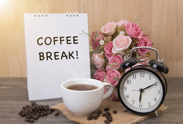 Xícara quente de café e despertador na mesa de madeira com flor de rosa
 - Foto, Imagem