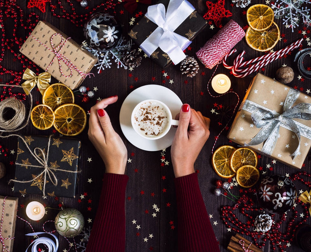 コーヒー カップの女性両手飲む飾られたお祝いテーブルにクリスマス ホリデー ギフト ボックス - 写真・画像