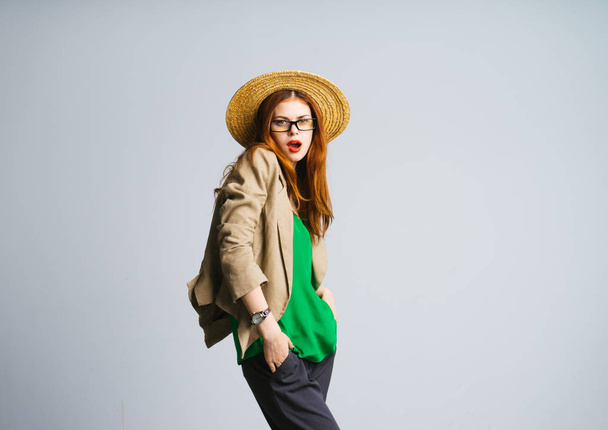 stylish girl in a straw hat, green jacket and glasses posing, looking at the camera - Photo, image