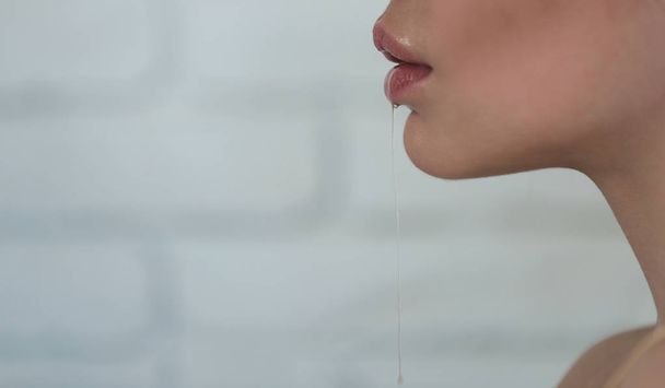 Частина жіночого обличчя з слиною з рота
 - Фото, зображення