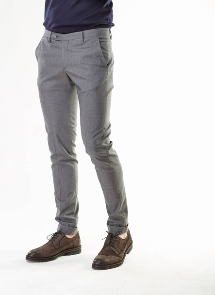 Man model posing in gray pants and brown shoes in light studio  - Foto, afbeelding