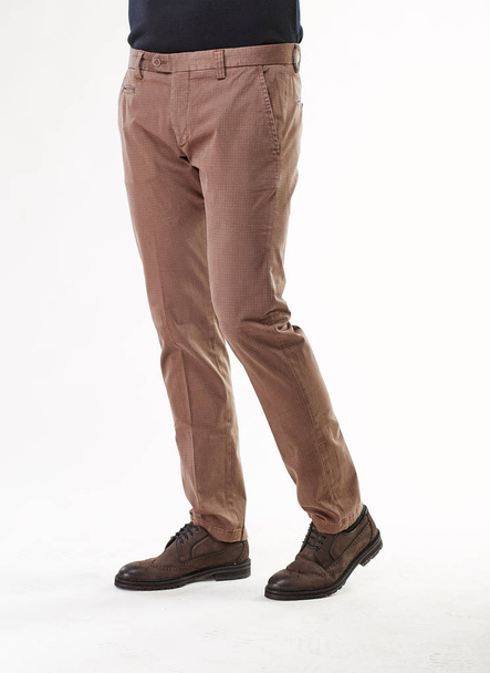Man model posing in light brown pants and brown shoes in light studio  - Fotó, kép