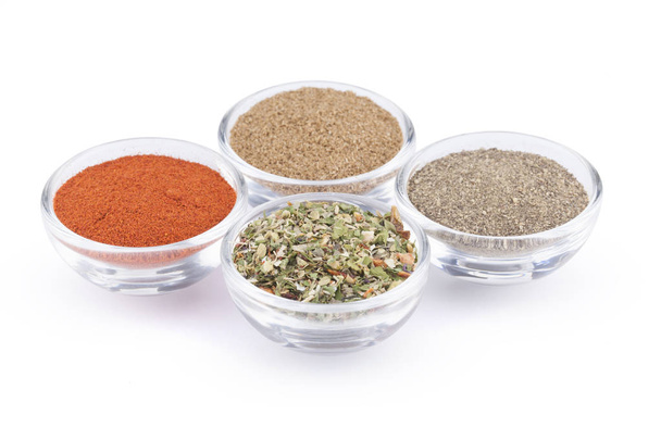 Ground black pepper, paprika, coriander and italian herbs in glass bowls isolated on white background - Foto, imagen