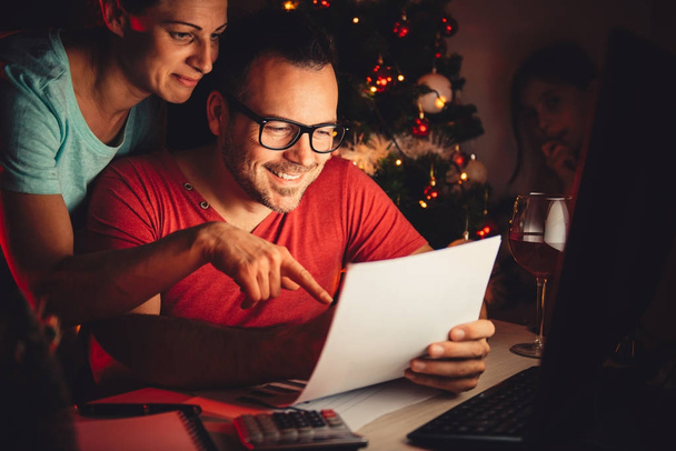 Mother and father reading daughter's christmas wish list with daughter peeking behind them - Φωτογραφία, εικόνα