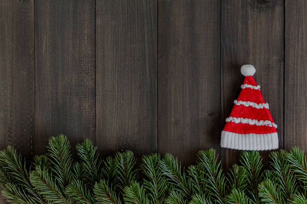 Karácsonyi fenyő fa ágai és santa záradék kalap rusztikus sötét fából készült háttér, a szöveg másolása szóközzel - Fotó, kép