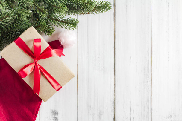 branches sapin de Noël avec santa claus chapeau et boîte cadeau sur fond blanc rustique en bois avec espace de copie pour le texte - Photo, image