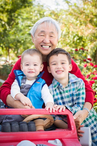 Feliz homem chinês adulto sênior brincando com seus netos de raça mista
 - Foto, Imagem