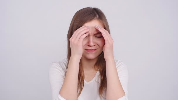Νεαρή γυναίκα έχει πονοκέφαλο, απομονωμένη σε γκρι φόντο - Πλάνα, βίντεο