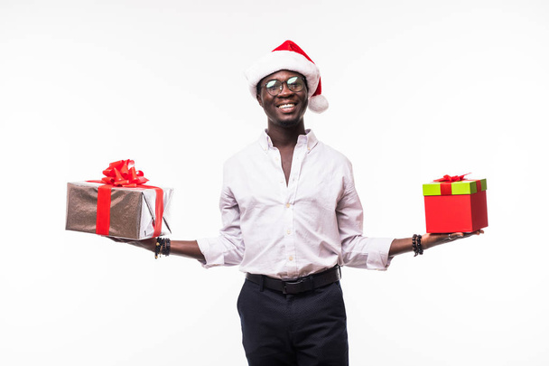 Homme afro-américain avec un grand sourire dans un chapeau de Père Noël avec deux boîtes-cadeaux isolées sur blanc
 - Photo, image