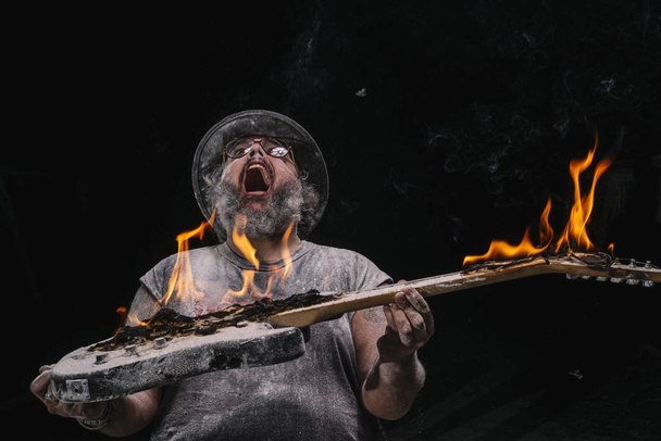 Человек с гитарой с огнем между мелом и дымовой пылью
 - Фото, изображение