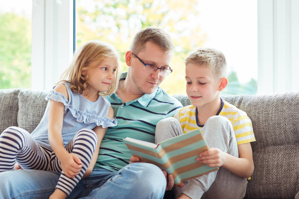 Young happy father reading book with cute children at home - Foto, Imagen
