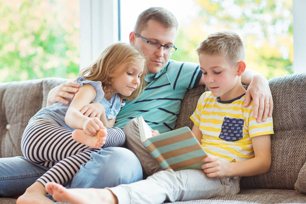かわいい子供たちが自宅で本を読んで若い幸せな父 - 写真・画像