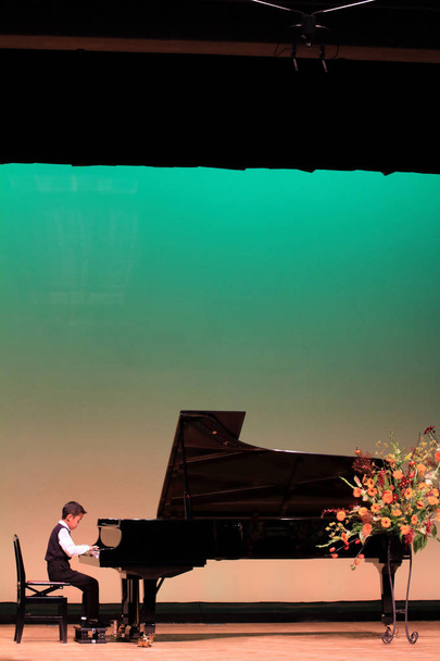 Japán fiú zongorázni a színpadon (második osztályos általános iskola) - Fotó, kép